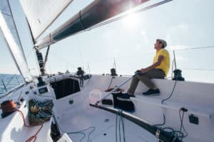 captain or sailor of sailboat steers yacht in wind